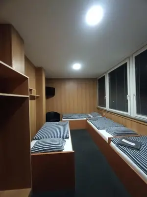 a room with three beds in a room with a window at Hotel a ubytovna Zimní stadion Slaný in Slaný