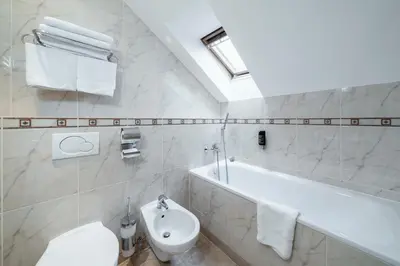 a white bathroom with a sink and a bath tub at Hotel Raffaello Prague in Prague