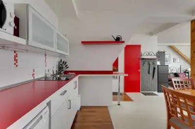 a kitchen with white cabinets and a red wall at Lenka's cozy Red studio + Lenka's cozy Gold apartment in Prague