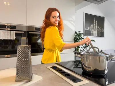a woman in a kitchen stirring a pot on a stove at ModaLoft Duplex by Rentez in Prague