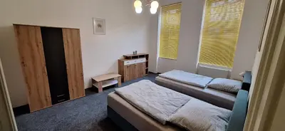 a bedroom with two beds and a table and windows at City center apartment Thomas No1 in Prague