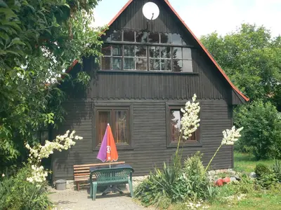 a house with a bench and an umbrella in front of it at Rekreační chata Hradištko in Hradištko