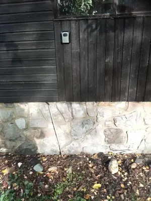 a black door with a stone wall in front at Rekreační chata Hradištko in Hradištko