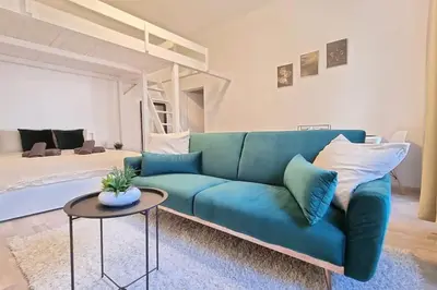 a living room with a blue couch and a bed at Finnem Rentals Pernerova in Prague