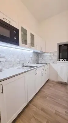 a white kitchen with a sink and a microwave at Finnem Rentals Pernerova in Prague