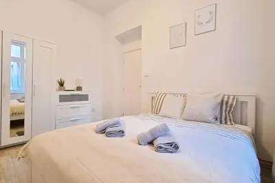 a white bedroom with a bed with towels on it at Finnem Rentals Pernerova in Prague