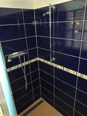 a blue tiled bathroom with a shower and a sink at Chaloupka v srdci Křivoklátska in Rakovník