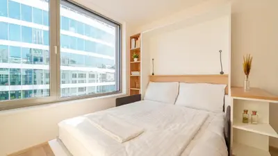 a bedroom with a white bed with a large window at MyMozart Residence by Rentez in Prague