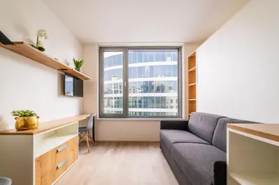 a living room with a couch and a desk and a window at MyMozart Residence by Rentez in Prague
