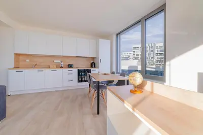 a kitchen with white cabinets and a wooden table at MyMozart Residence by Rentez in Prague