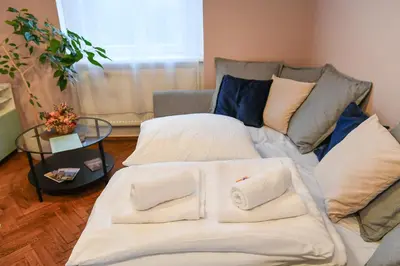 a large white bed with pillows and a couch at ANGEL apartment Prague in Prague
