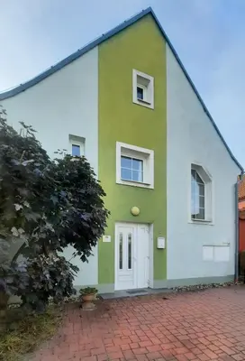 a green and white house with a white door at Apartmán Franz Josef in Hošťka