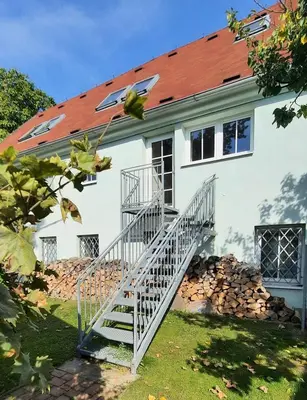 a white house with a staircase in front of it at Apartmán Franz Josef in Hošťka