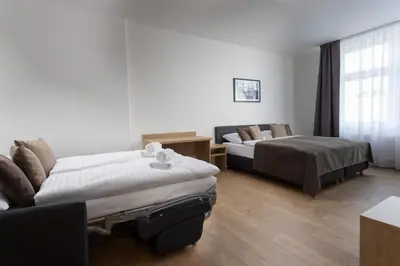 a hotel room with two beds and a couch at Residence Morris Mladá Boleslav in Mladá Boleslav