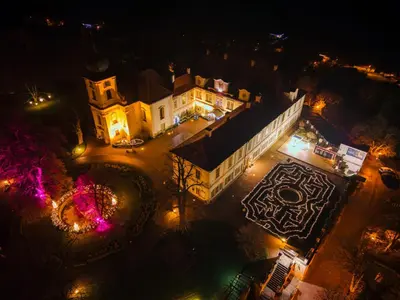 an aerial view of a building at night with lights at Chateau Loucen Garden Retreat in Loučeň
