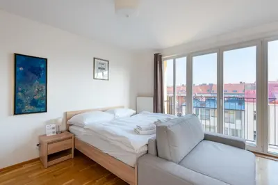 a white bedroom with a bed and a couch at Sunny Safron apartment in Prague