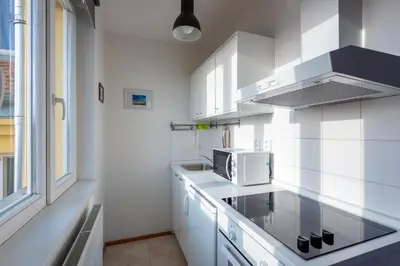 a white kitchen with a microwave and a stove at Sunny Safron apartment in Prague