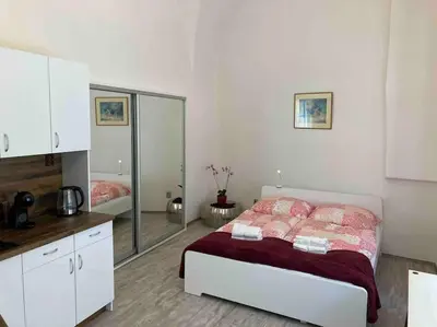 a white bedroom with a bed and a mirror at Studio in gothic house, 50m to the Old Town Square in Prague
