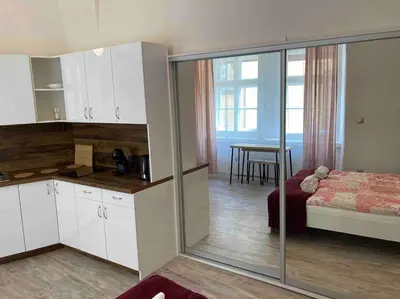a kitchen with white cabinets and a bed and a table at Studio in gothic house, 50m to the Old Town Square in Prague