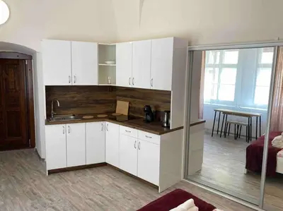 a kitchen with white cabinets and a table in a room at Studio in gothic house, 50m to the Old Town Square in Prague