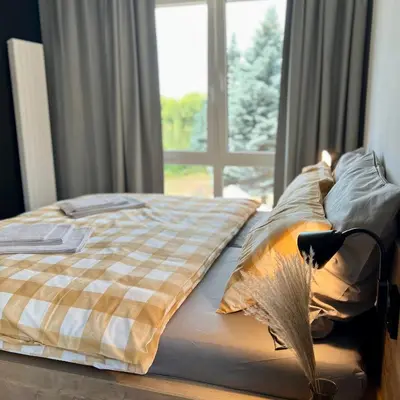 a bed with a checkered blanket and a window at Penzion Racek in Tuchlovice