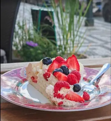 a slice of cake with berries on a plate at Hradčany apartment with green energy in Prague