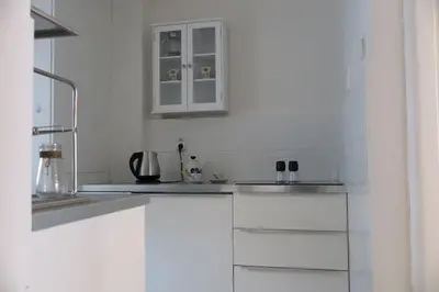 a white kitchen with white cabinets and a sink at Hradčany apartment with green energy in Prague