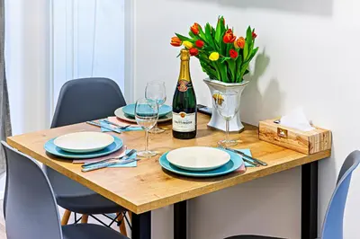 a dining table with a bottle of champagne and flowers at MamaStay Andel Apartments in Prague