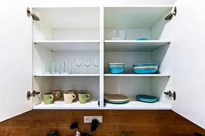 a white cabinet filled with plates and bowls at MamaStay Andel Apartments in Prague