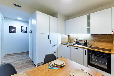a kitchen with white cabinets and a wooden table at MamaStay Andel Apartments in Prague