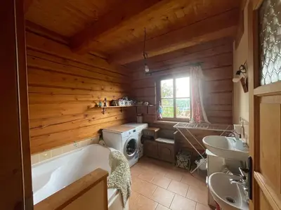 a bathroom with a tub and a sink and a washing machine at Roubenka v Posázaví in Zbizuby