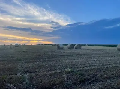 a field with hay bales in a field with the sunset at Roubenka v Posázaví in Zbizuby