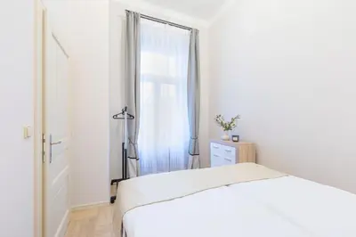 a white bedroom with a bed and a window at Palace Petrarca in Prague