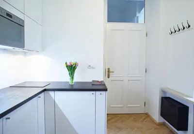 a kitchen with white cabinets and a vase of flowers at Lovely Lila apartment in Prague