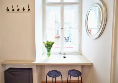 two chairs sitting under a window with a vase of flowers at Lovely Lila apartment in Prague