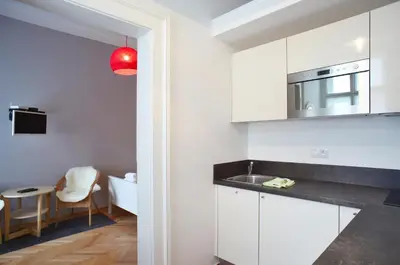 a kitchen with white cabinets and a red light at Lovely Lila apartment in Prague