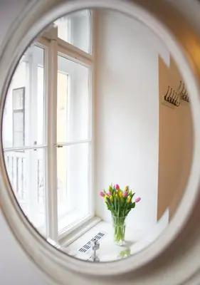 a mirror reflecting a window with a vase of flowers at Lovely Lila apartment in Prague
