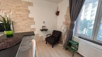 a living room with a black chair and a stone wall at Bastien Studio near Airport in Prague
