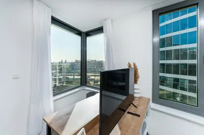 a living room with a tv and large windows at Rentero MyMozart Apartments Prague in Prague