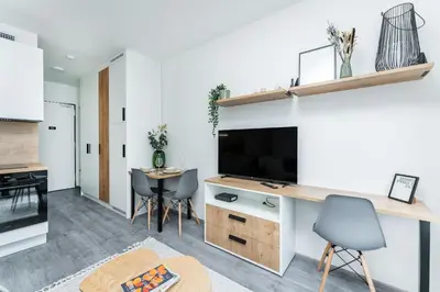 a living room with a large television and a table at Rentero MyMozart Apartments Prague in Prague