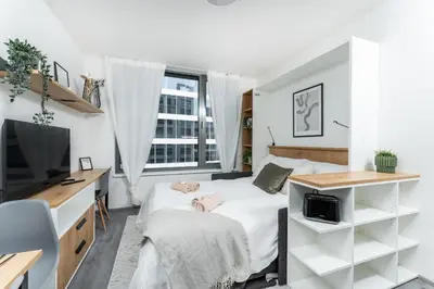 a bedroom with a bed and a desk and a tv at Rentero MyMozart Apartments Prague in Prague