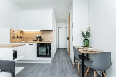 a kitchen with white cabinets and a table with chairs at Rentero MyMozart Apartments Prague in Prague