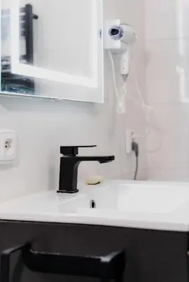 a bathroom sink with a black faucet and a mirror at Apart Comfort in Prague