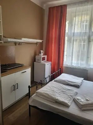 a bedroom with a bed and a kitchen with a window at Pension Sunflower in Prague