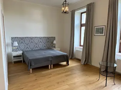 a bedroom with a bed and a table and a window at Zámek Jenišovice in Býkev