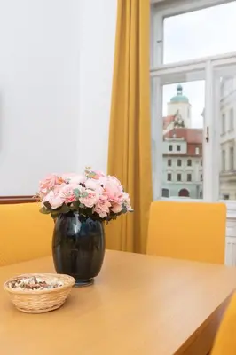 a black vase with pink flowers on a table at Moonlight Apartments Old Town in Prague