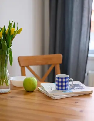 a table with a book and a cup and a green apple at Cosy central apartment in Žižkov in Prague