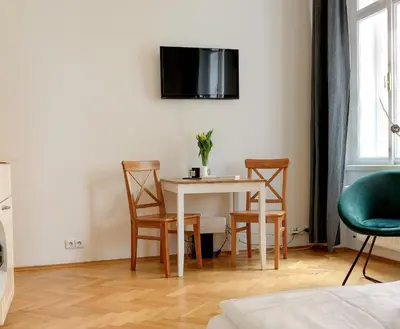 a room with a table and chairs and a tv on the wall at Cosy central apartment in Žižkov in Prague
