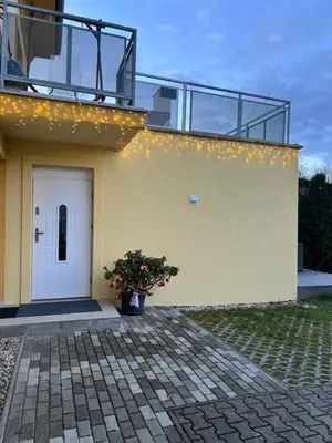 a yellow house with a balcony and a potted plant at Appartment Pruhonice & terrace in Pruhonice