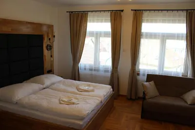 a bedroom with a bed and a couch and windows at Penzion Radost in Poděbrady